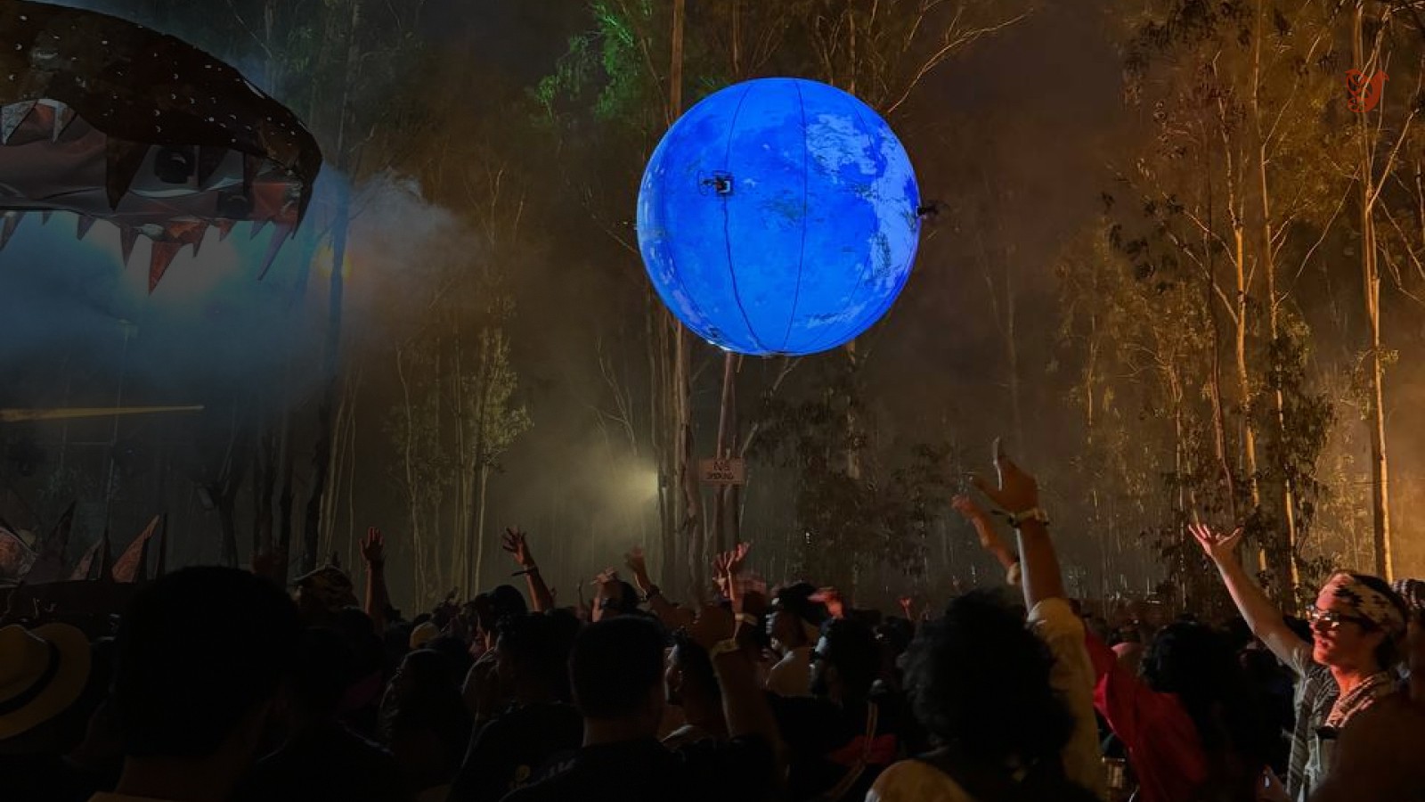 Gece festivalde ağaçların arasında süzülen ışıklı gezegen zeplini